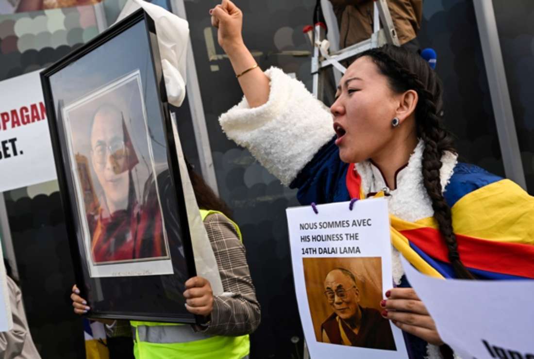 A woman holds a sign reading 'We are with his holiness the 14th Dalai Lama' during a rally in support of Tibetan spiritual leader the Dalai Lama after a video triggered a backlash on social media in which he asks a boy to suck his tongue, in Paris, on April 22