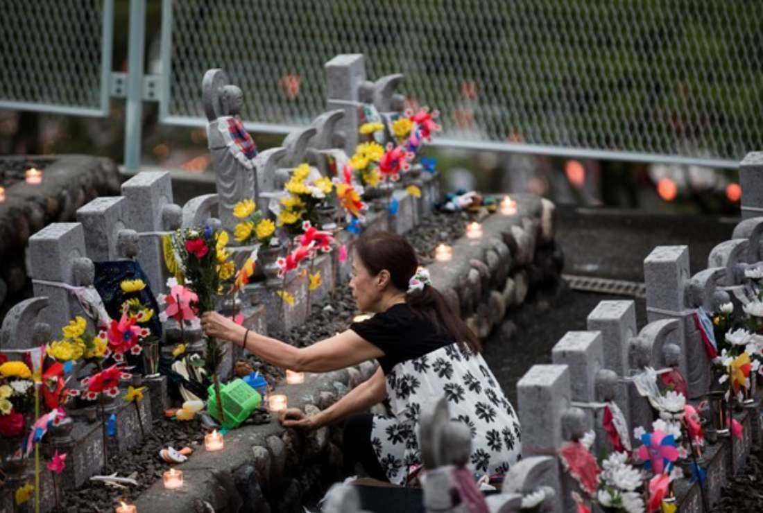 A woman places flowers in front of a 'jizo' statue of her aborted child in Jizoji Buddhist Temple in Oganomachi, Saitama prefecture, for the souls of unborn children and those who died at a young age, during the Obon prayers period, in August 2018