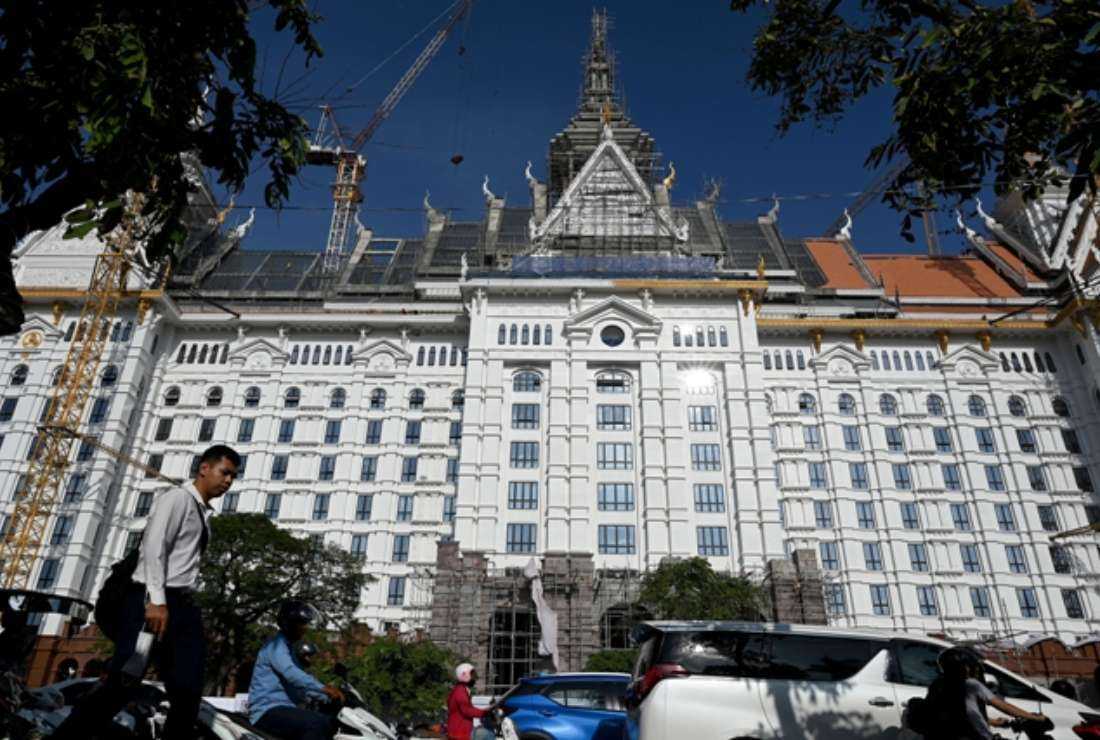 Pedestrians and vehicles pass in front of the Ministry of Interior under construction in Phnom Penh on May 31. Three members of the Coalition of Cambodian Farmers Community (CCFC) were released on bail in Cambodia after they confessed to charges of plotting a 'peasant revolution.' 