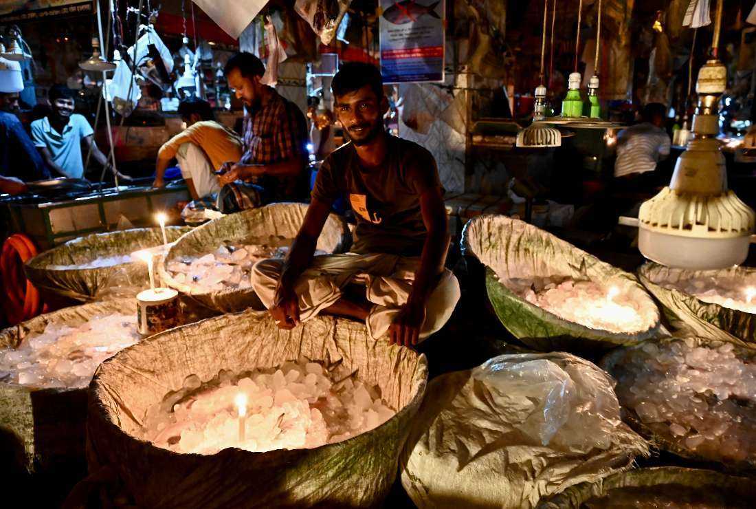Vendors use candles at a fish market during a power blackout in Dhaka on Oct. 4, 2022. This year the 1,320-megawatt government-run Payra Power Plant in southern Bangladesh has been shut amid a surging electricity demand due to a sweltering heatwave