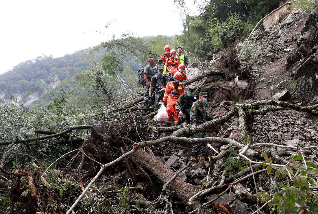 This photo taken on Sept. 6, 2022, shows rescuers walking past uprooted trees from a landslide as they head to an earthquake-affected area following a 6.6-magnitude earthquake that struck Sept. 5, in Shimian county, Ya'an city, in China's southwestern Sichuan province