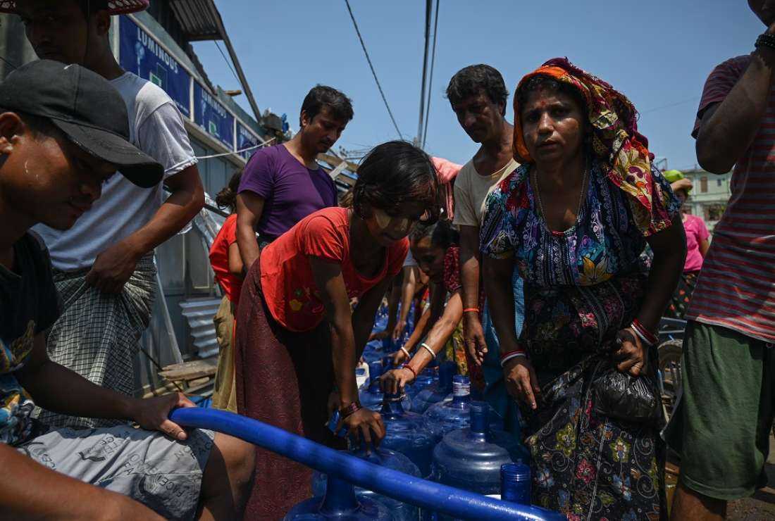 People queue for drinking water at a distribution point in Sittwe on May 17, 2023, in the aftermath of Cyclone Mocha's landfall. Villagers are trying to piece together ruined homes and waiting for aid and support