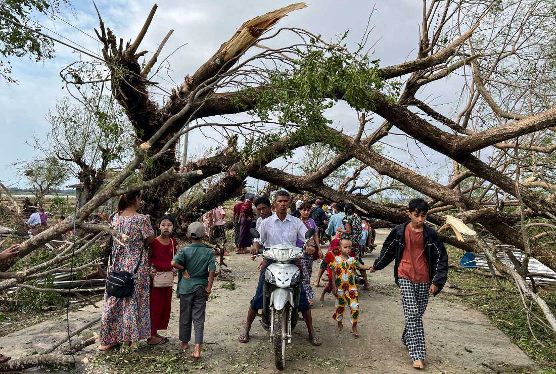 Residents walk past fallen trees in Kyauktaw in Myanmar's Rakhine state on May 15 after Cyclone Mocha crashed ashore