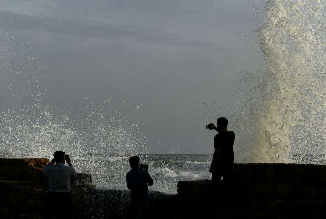 People take photos of high tides at a beach before the due onset of cyclone, in Karachi on June 12