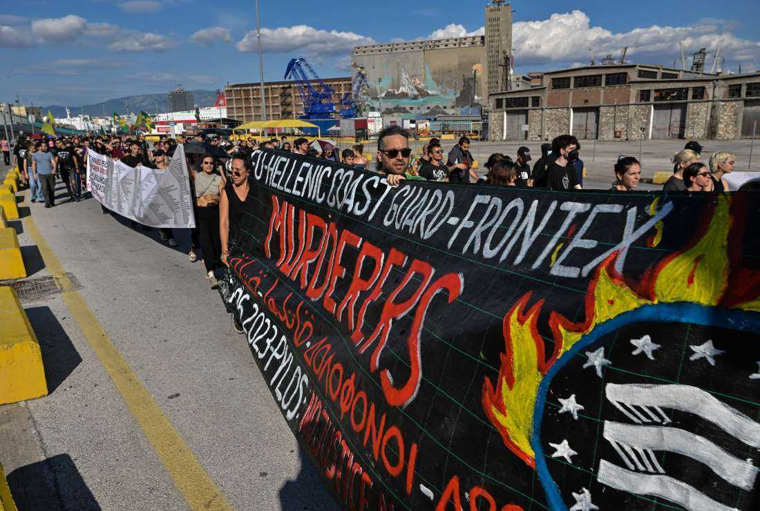 People hold a banner during a protest march to the Frontex and Hellenic Coastguard headquarters in the port of Piraeus near Athens, on June 18 following the deadly shipwreck which cost the lives of at least 78 migrants