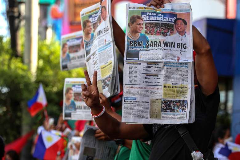 Supporters of Philippine presidential candidate Ferdinand Marcos Jr. hold newspapers with coverage of his landslide victory outside his campaign headquarters in Mandaluyong City, Metro Manila, on May 10
